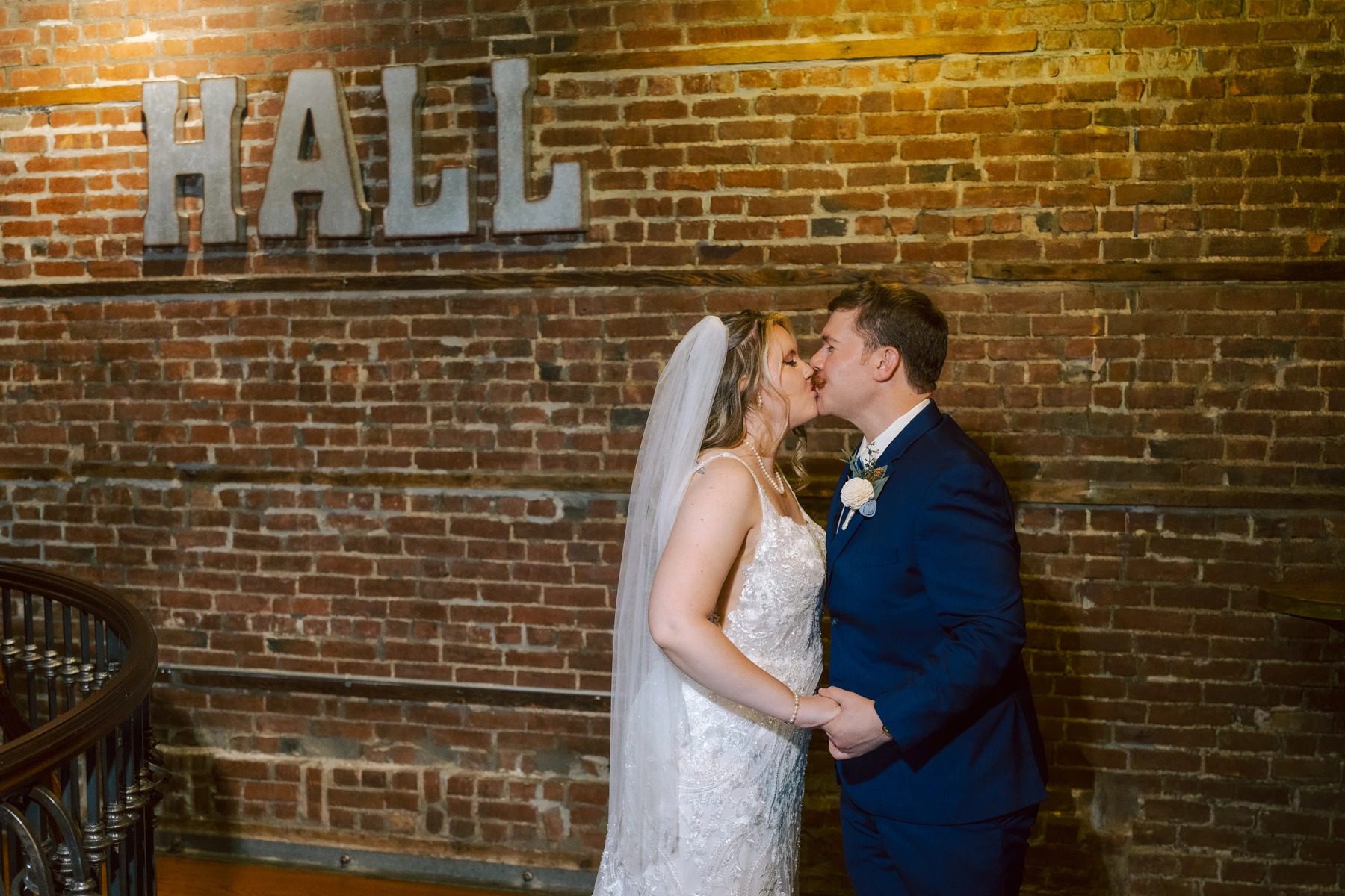 Bride and groom kiss beneath a glowing HALL sign at their wedding reception. — Wedding at Dramatic Hall, peekskil, ny