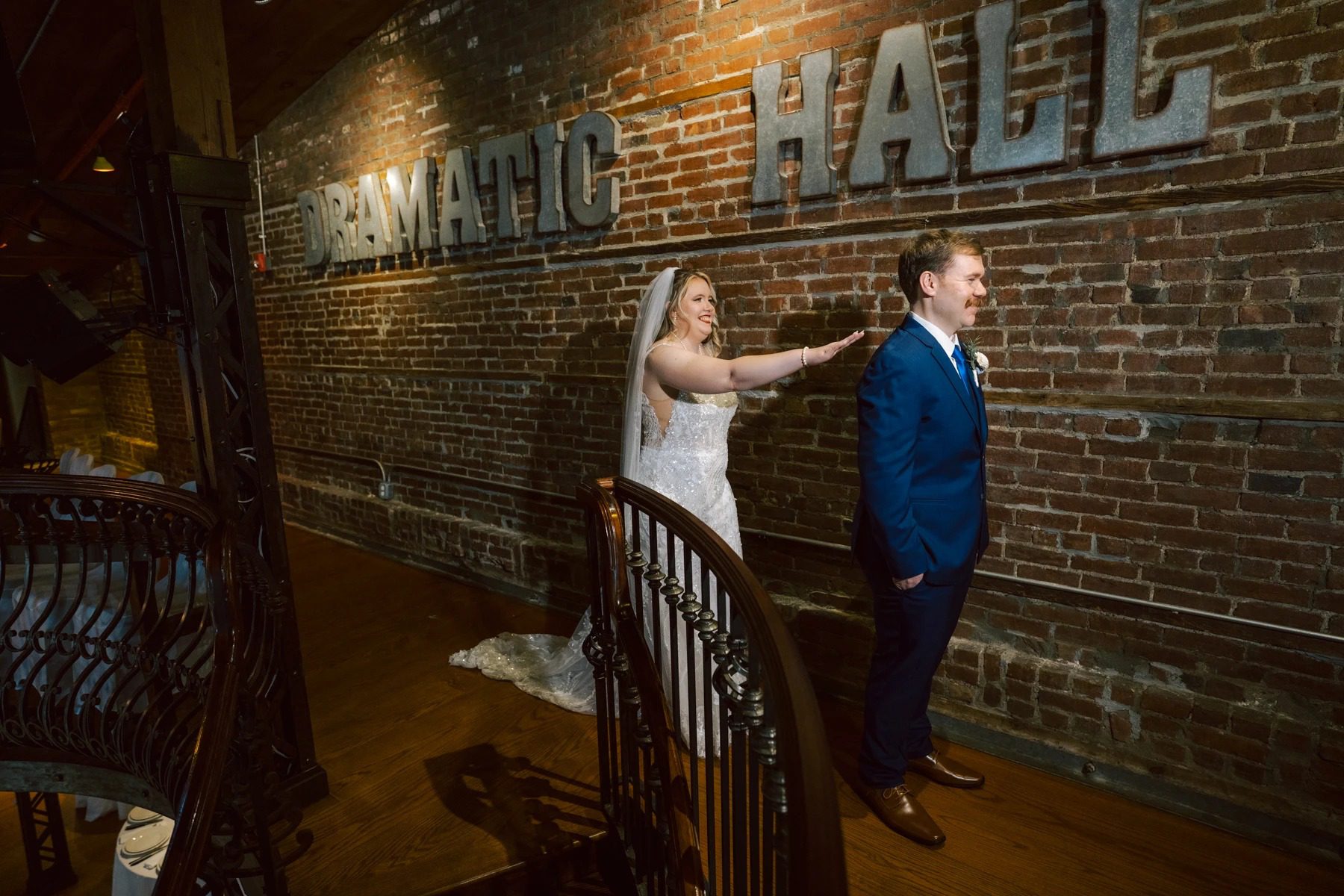 Bride and groom posing together against a brick wall with illuminated signage during their wedding reception. — Wedding at Dramatic Hall, peekskil, ny