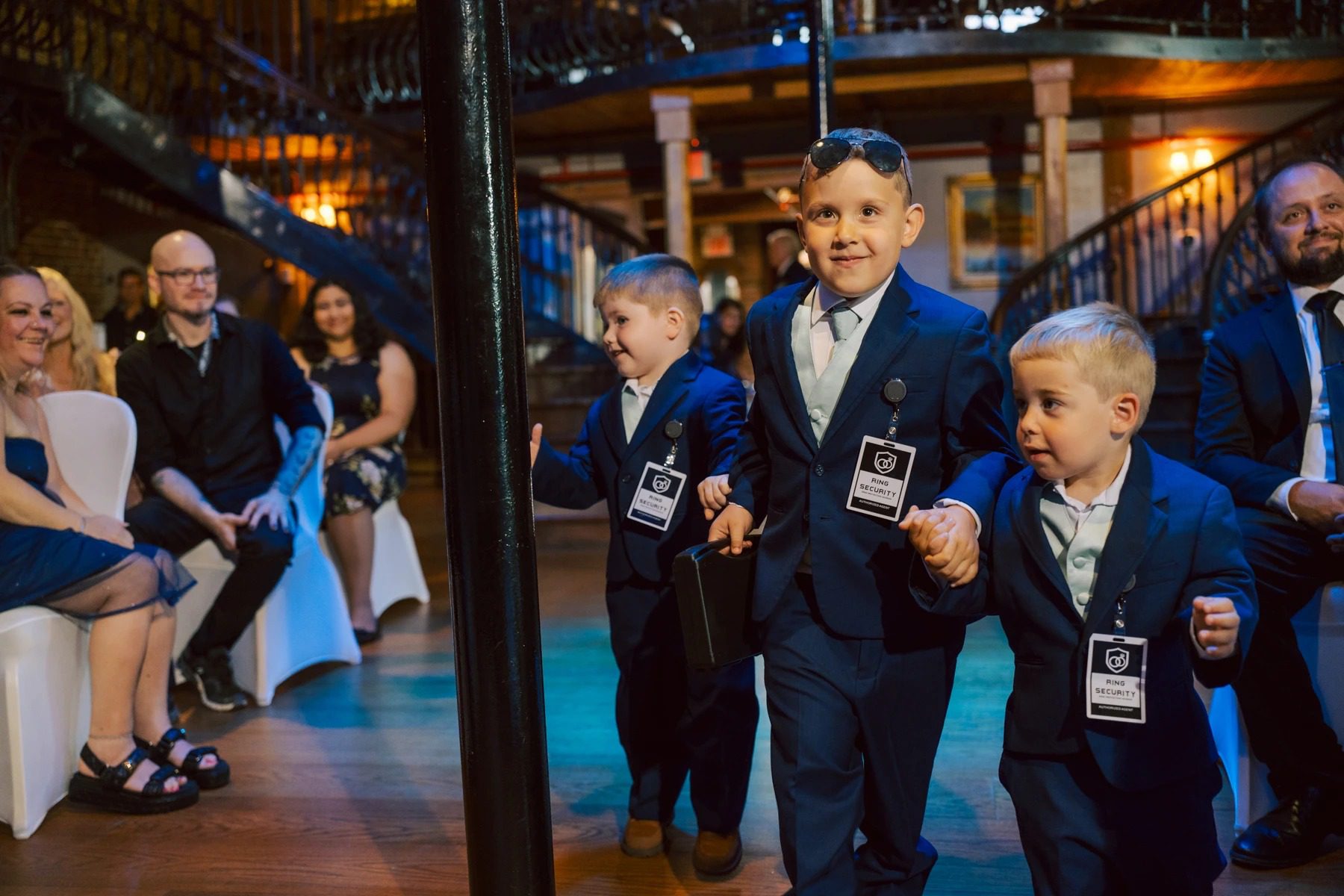 Three young boys in formal suits walk across a lit dance floor while adults watch from the sides. — Wedding at Dramatic Hall, peekskil, ny